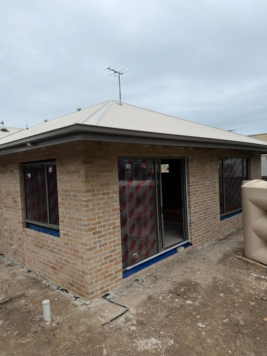 Brickwork complete to the rear corner of the Moorabbin knockdown rebuild, with the roof on and windows installed